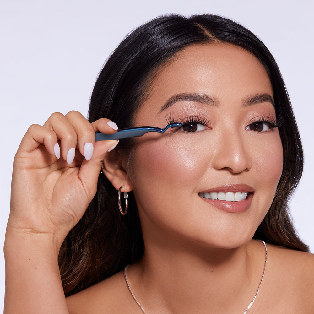 Model bringt künstliche Wimpern mit blauem Applikator am oberen Wimpernkranz an