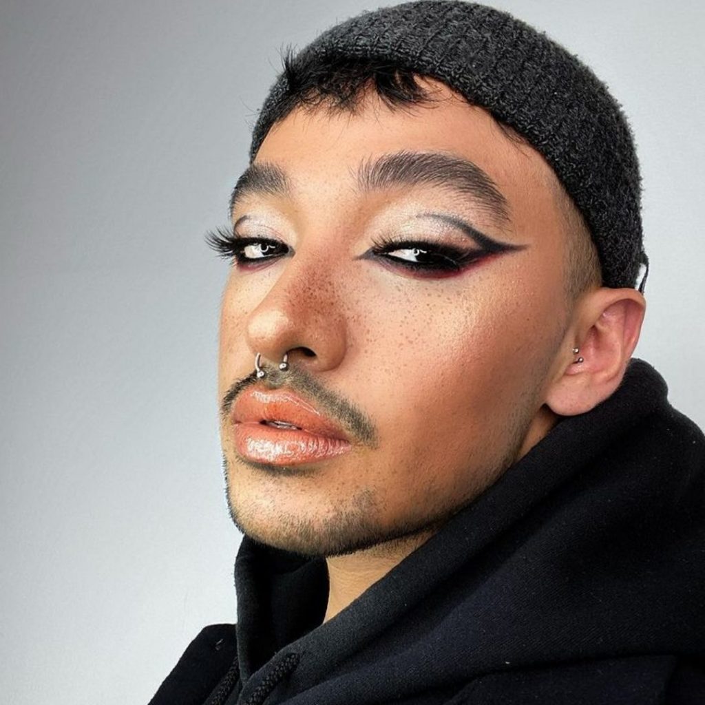 Ein Mann hat einen coolen Make Up Look mit verführerischen Lashes.