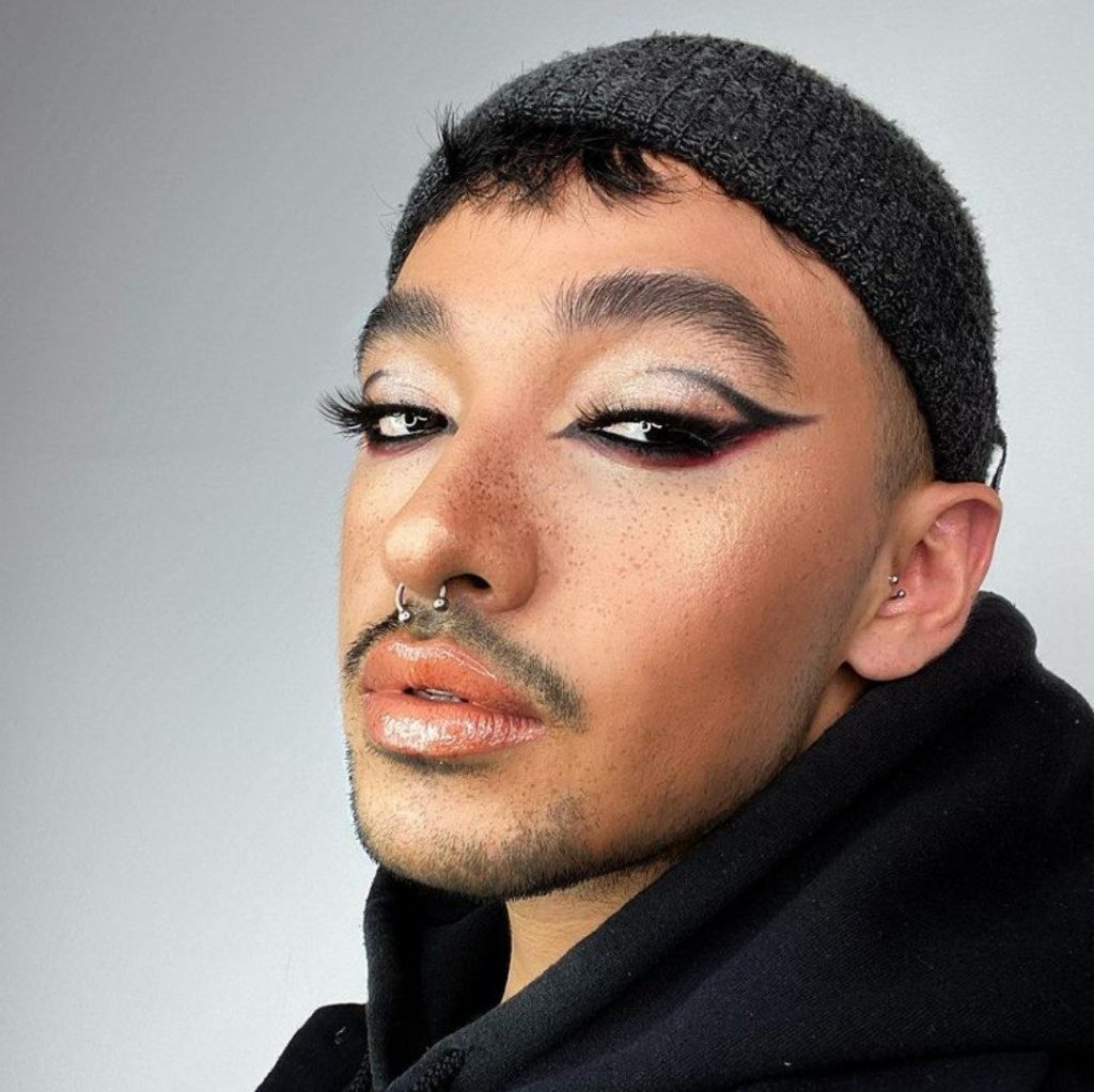 Ein Mann trägt ein cooles Make Up mit verführerischen Wimpern.
