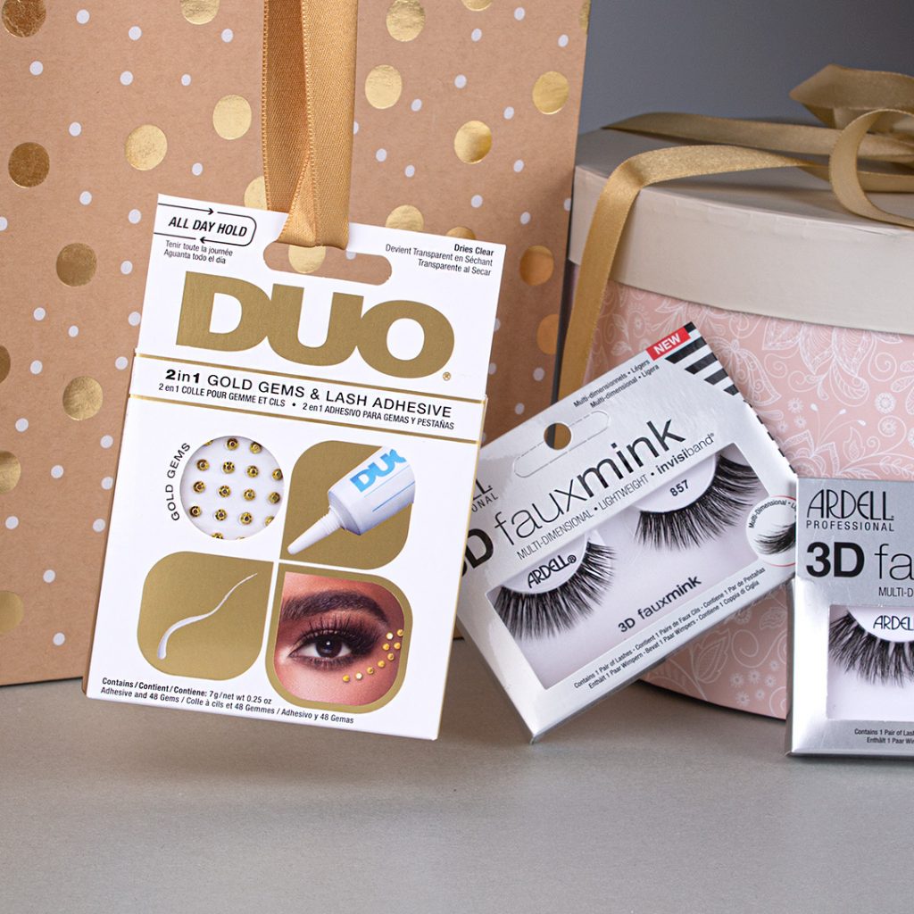 DUO Gold Gems und 3D Fauxmink Lashes lehnen an und bei zwei Geschenkeboxes, auf weißem Hintergrund.