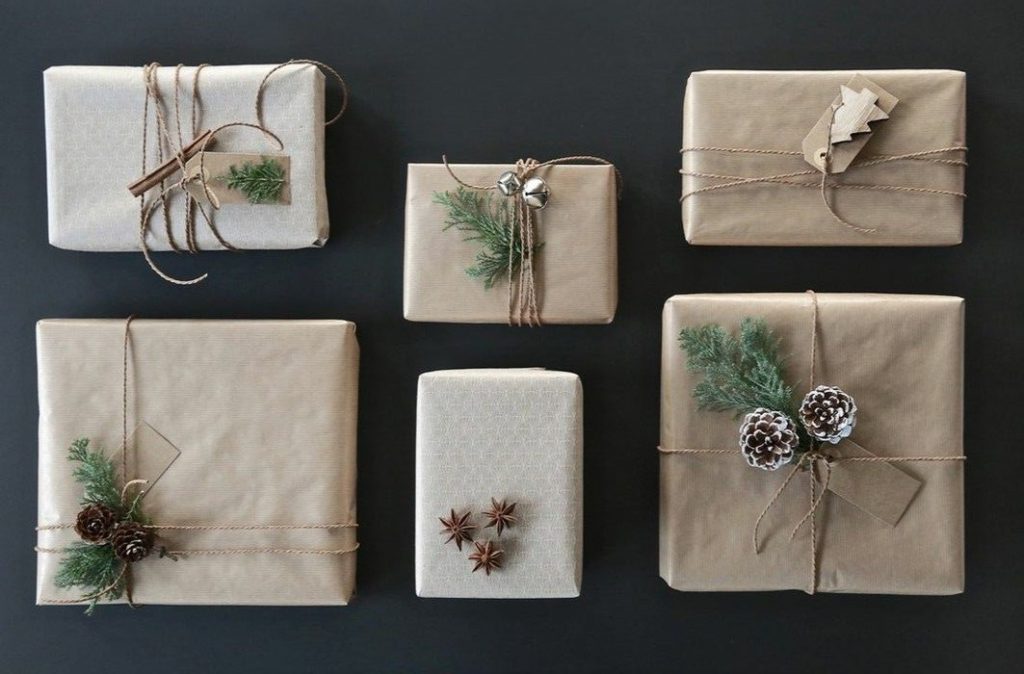 Für den Geschenke-Guide sind auf blauem Hintergrund Verpackungsideen zu sehen. Sechs Geschenke liegen in Braun und Creme Tönen ordentlich auf dem Hintergrund.