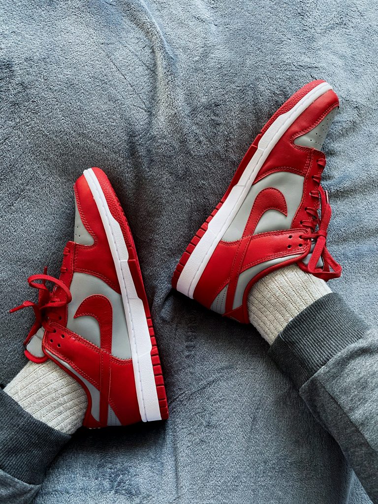 Auf einer dunklen Fließdecke sind rote Nike Schuhe zu sehen, passend zum Frühlingslook.